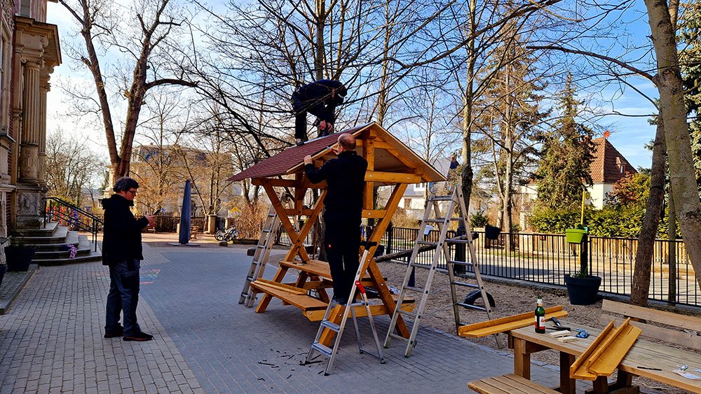 Fleißige Männer bauen die Sitzgruppe auf und befestigen das Dach.